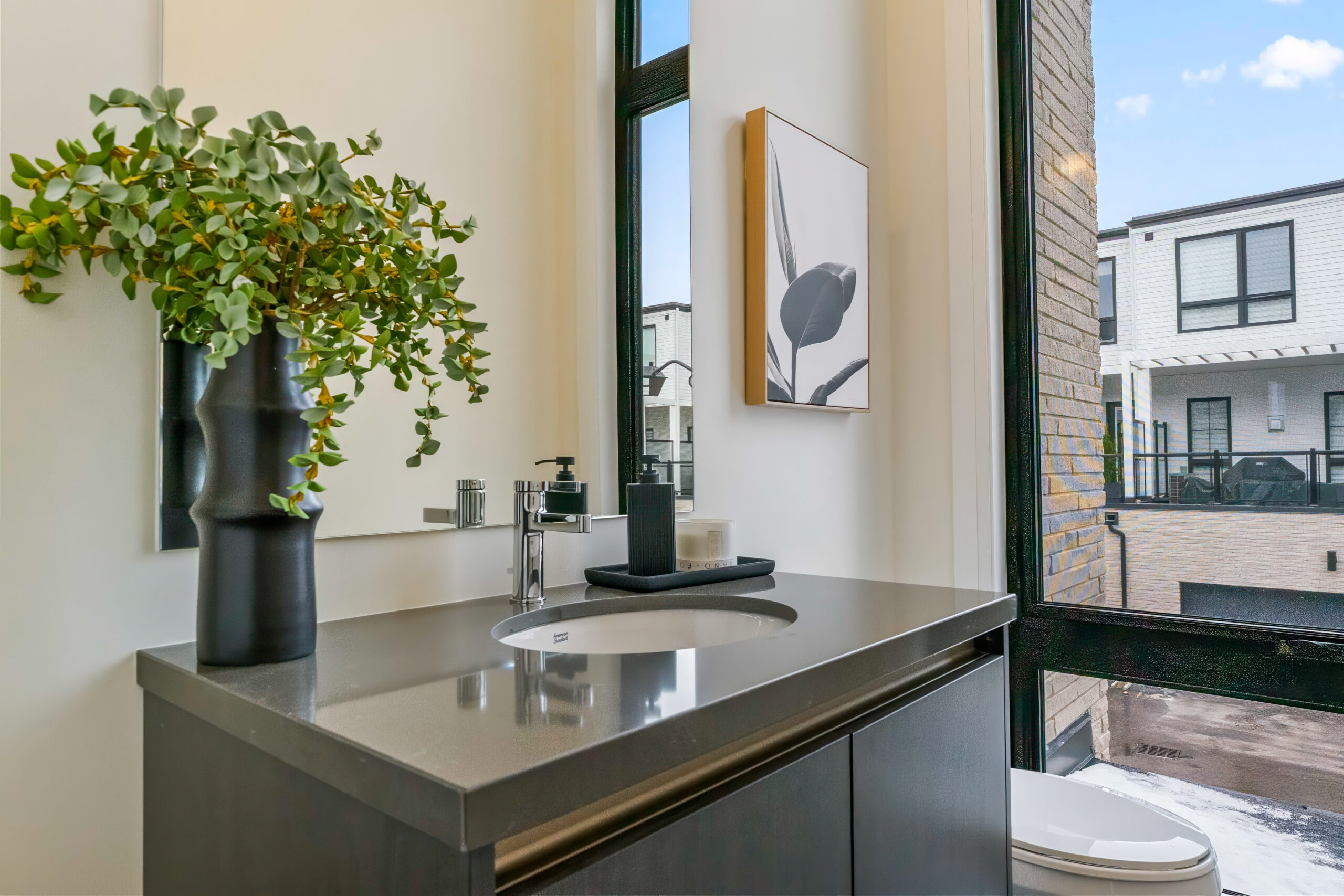 Modern bathroom with a sleek vanity, plants, and large windows.