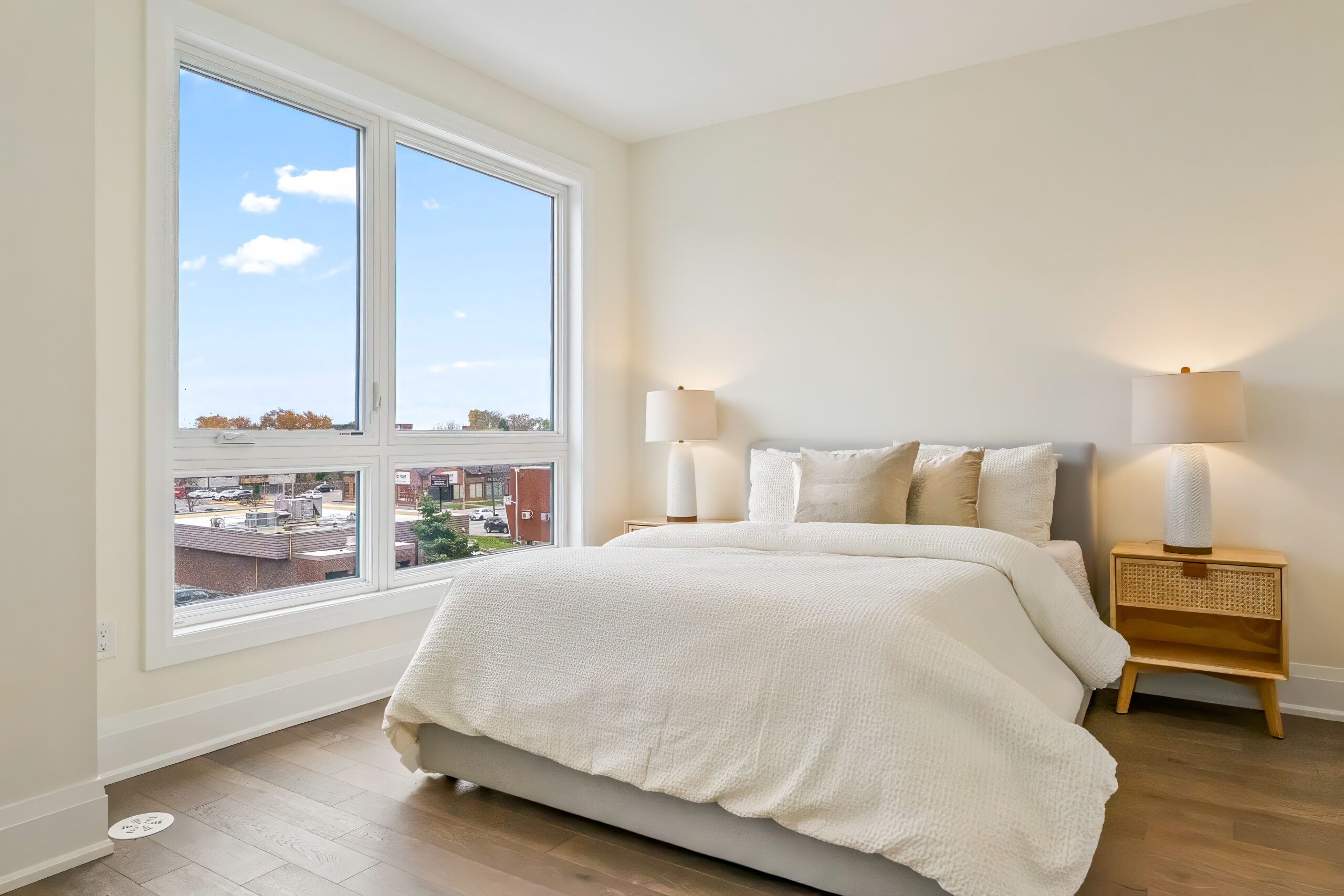 Bright bedroom with large windows, a cozy bed, and stylish lamps