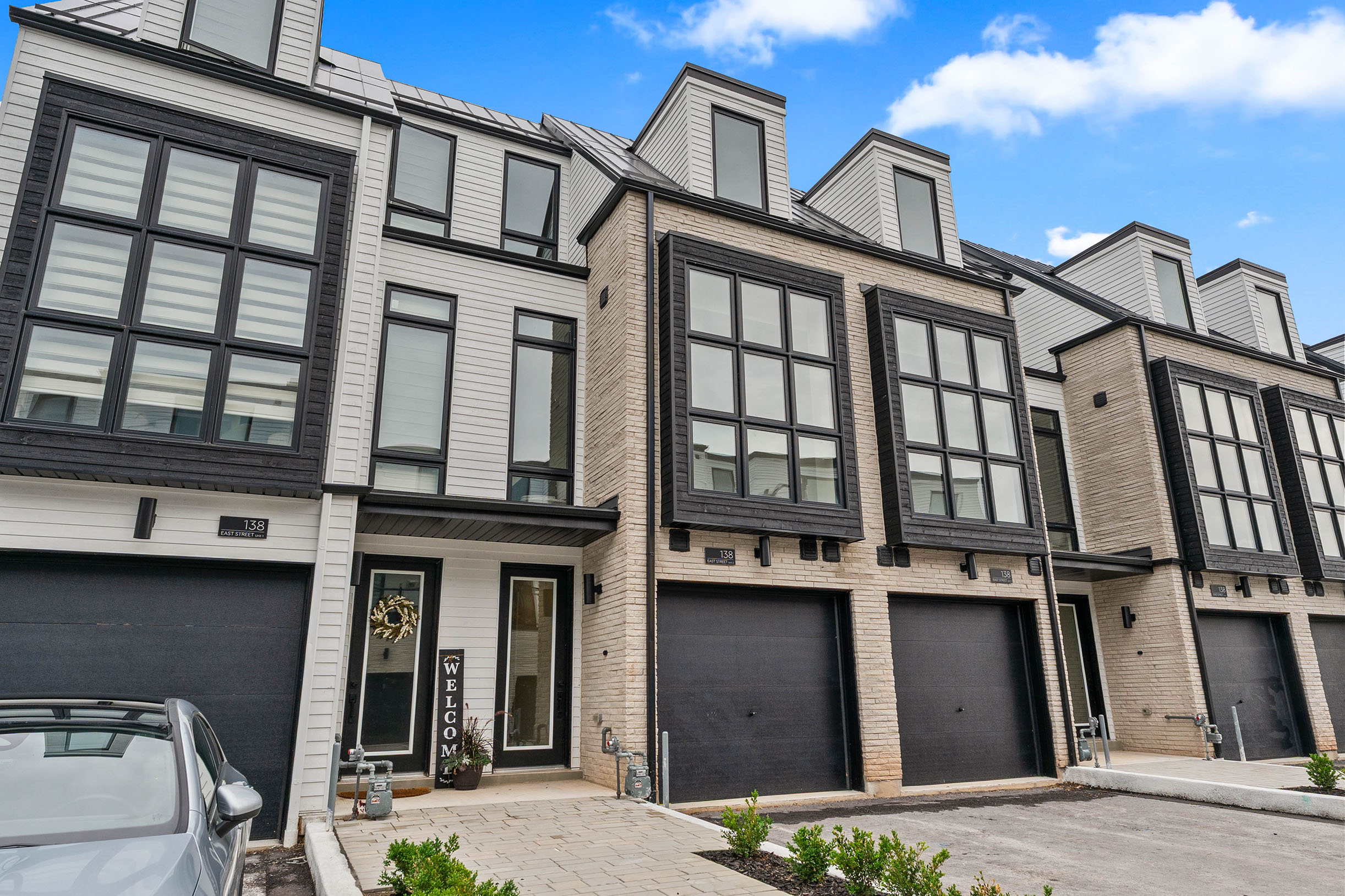 Modern townhouses with large windows and garages under a blue sky