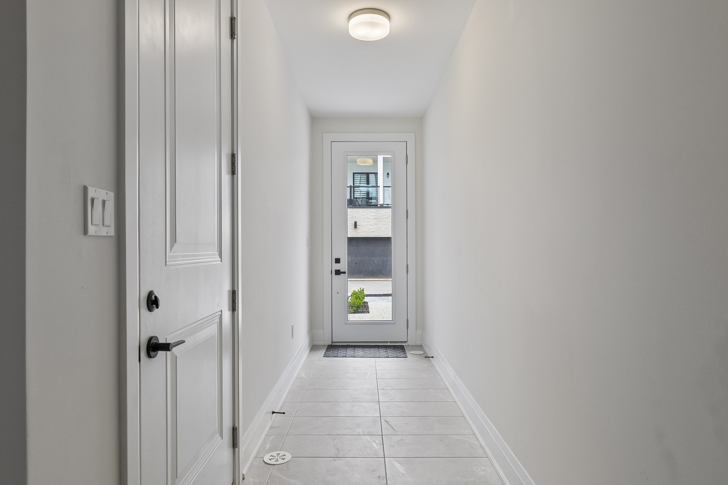 Bright hallway leading to a glass door with a potted plant outside