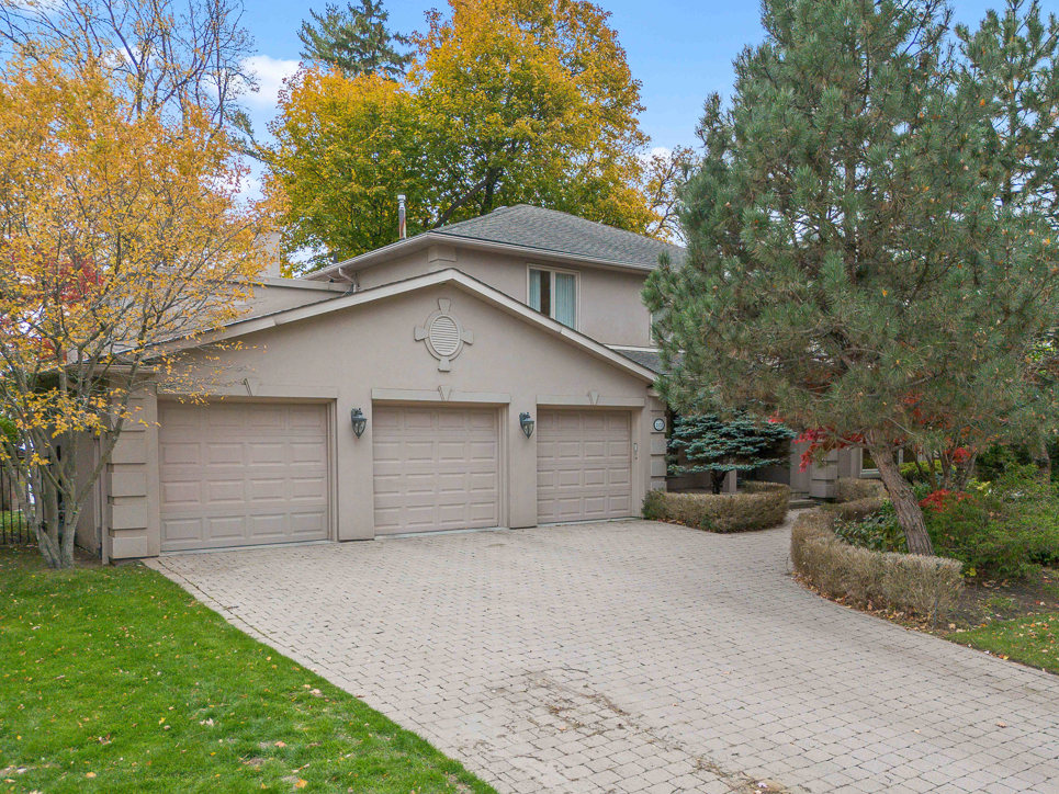 Two-car garage with a paved driveway and autumn foliage nearby