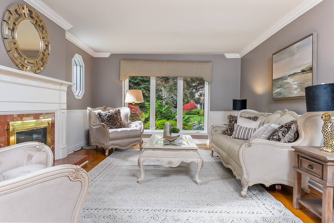Elegant living room with beige furniture and large windows overlooking greenery