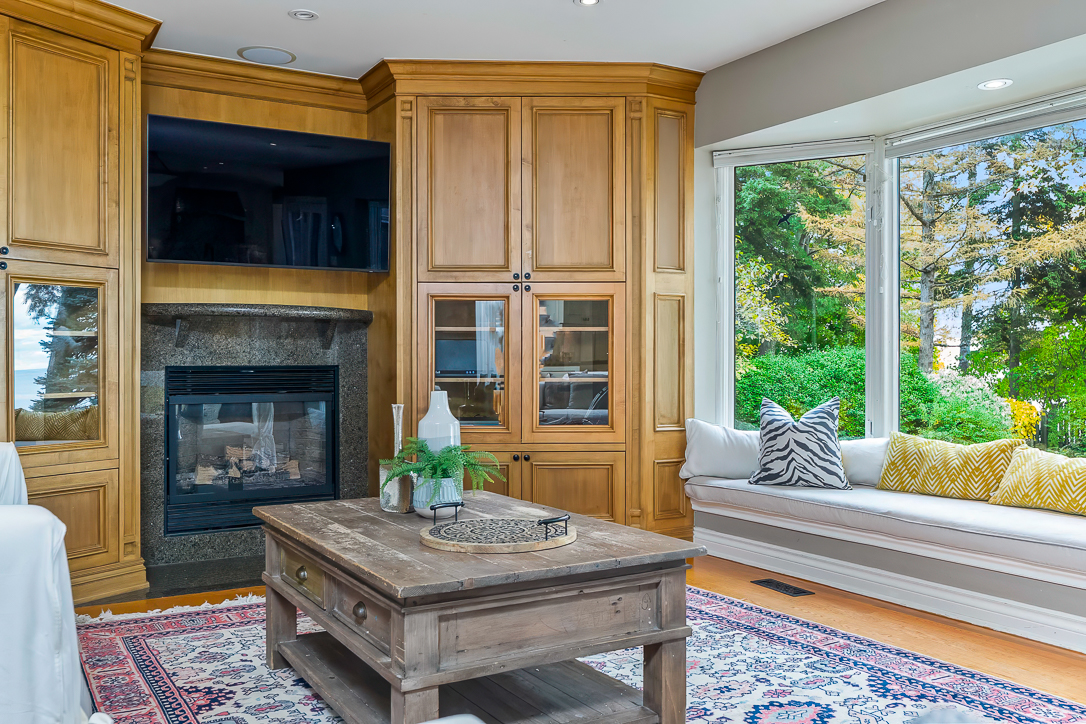 Cozy living room with wooden cabinetry, fireplace, and window seat