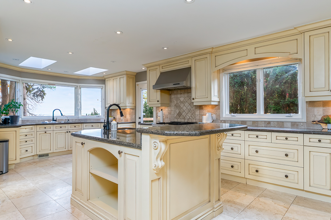 Spacious kitchen with cream cabinetry and granite countertops, featuring large windows
