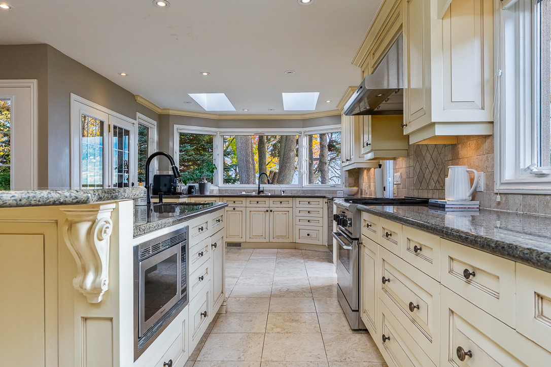 Modern kitchen with cream cabinets, granite countertops, and large windows
