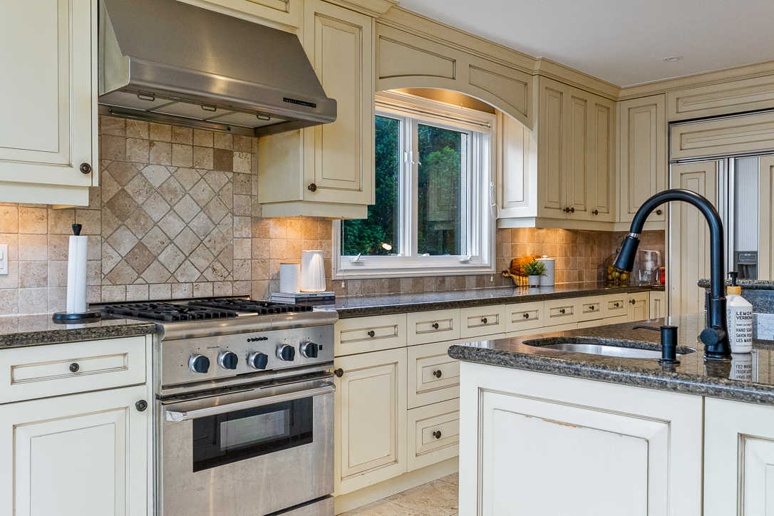 Modern kitchen with cream cabinets, granite countertops, and stainless steel appliances