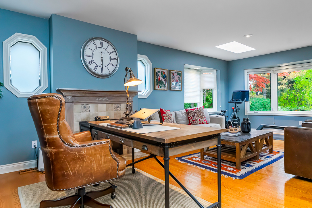 Cozy home office with a wooden desk, leather chair, and blue walls