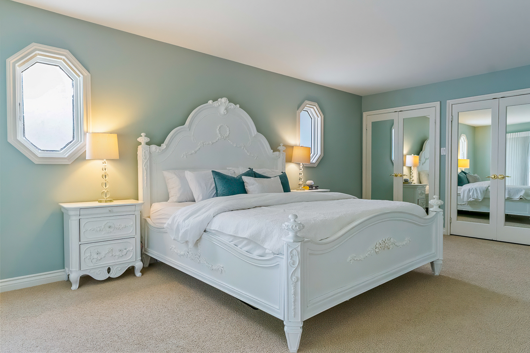 Elegant bedroom with a white bed, blue accents, and mirrored closet doors