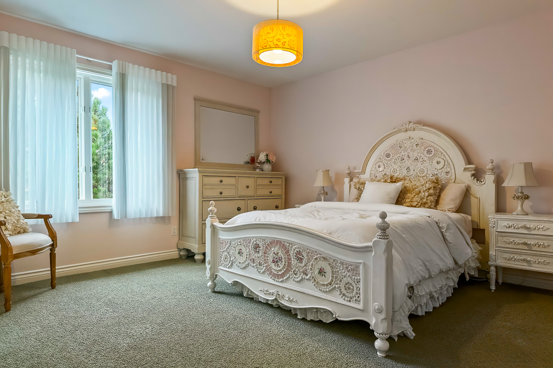Cozy bedroom with pink walls, white furniture, and a decorative bedspread