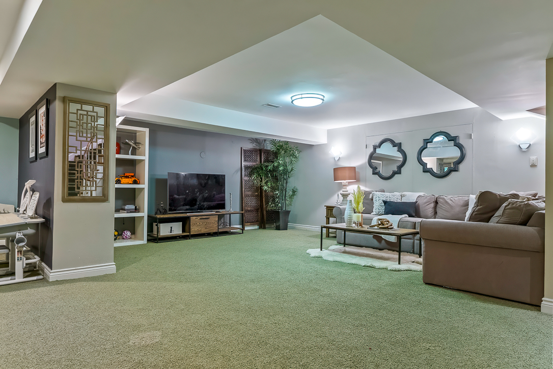 Cozy basement living area with a sofa, TV, and decorative mirrors