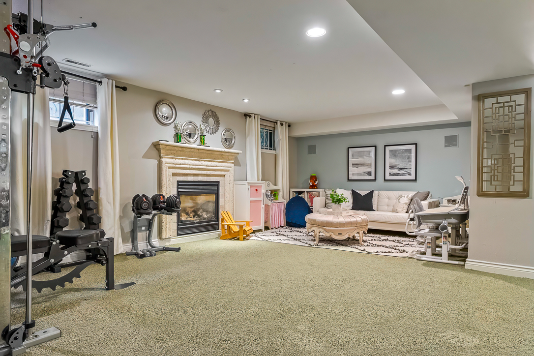 Cozy basement living area with fireplace, workout equipment, and seating