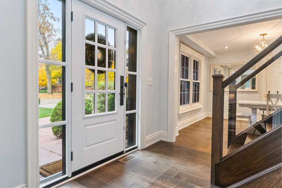 Bright entryway with a glass-paneled door and wooden staircase