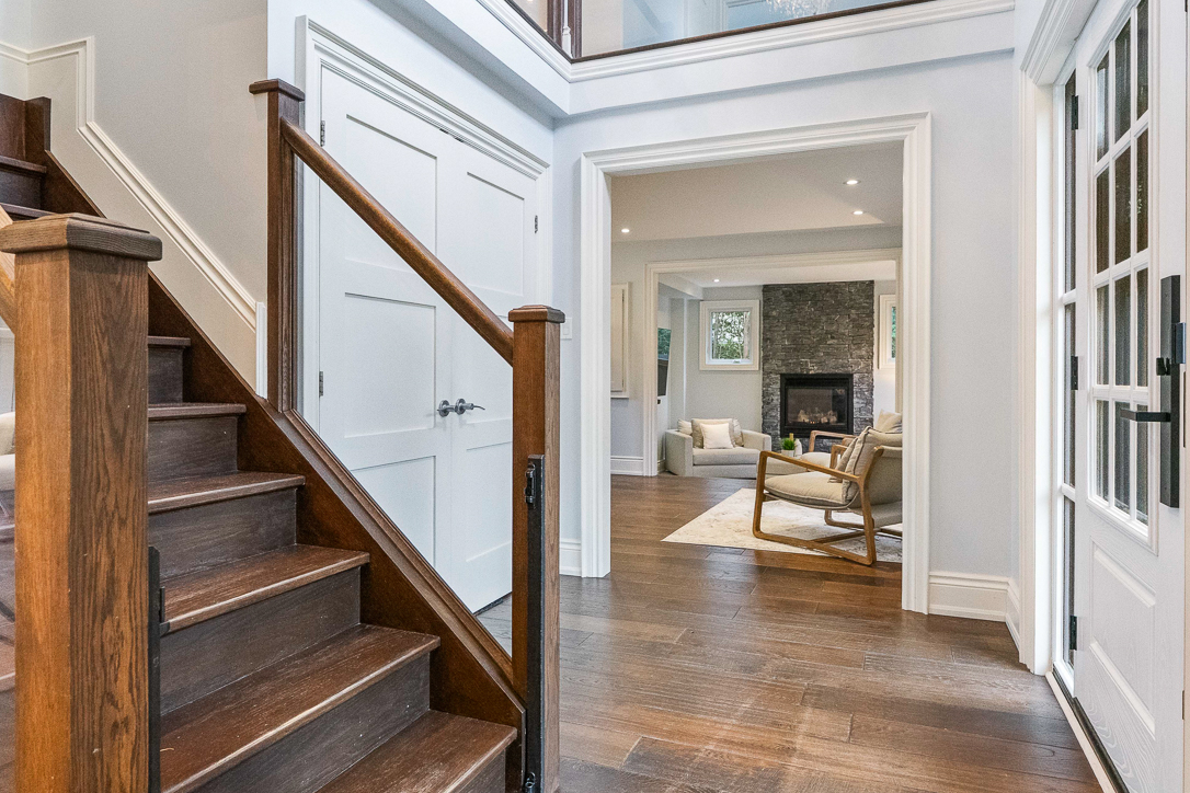 Bright entryway with wooden stairs and open living area visible beyond