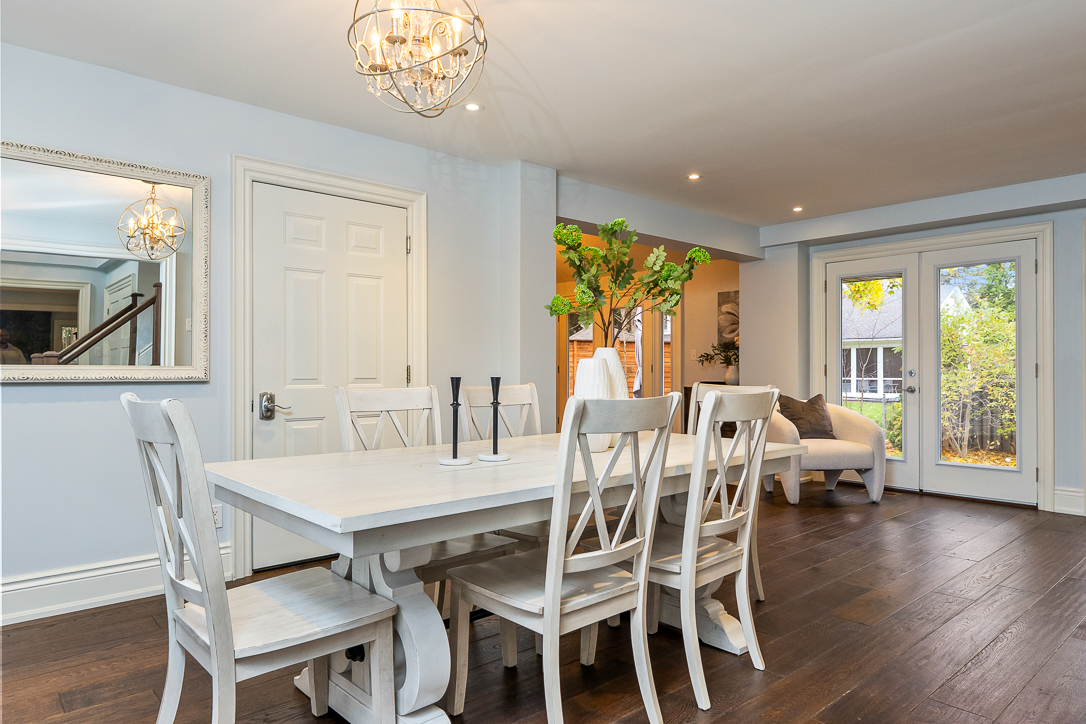 Bright dining area with a white table, chairs, and a chandelier