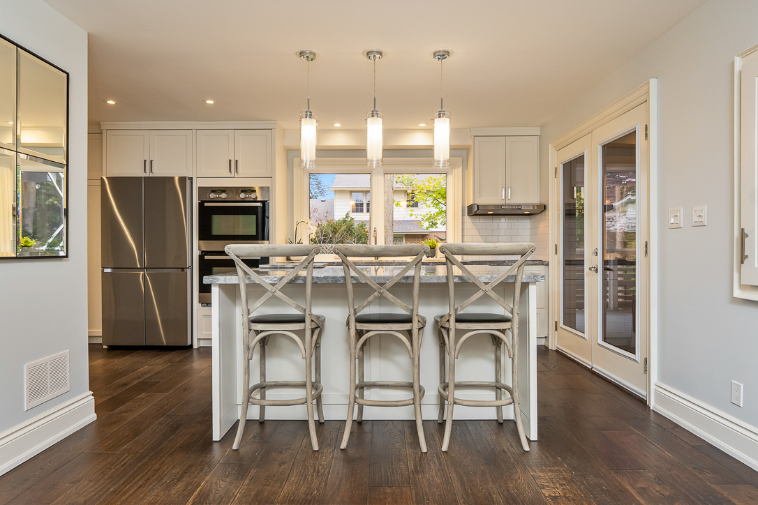 Modern kitchen with white cabinetry, stainless steel appliances, and a large island.