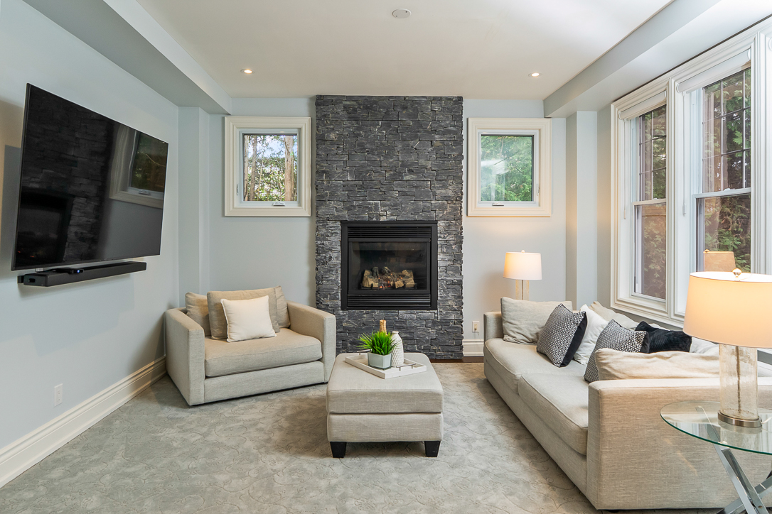 Cozy living room with a stone fireplace, light gray sofas, and a TV