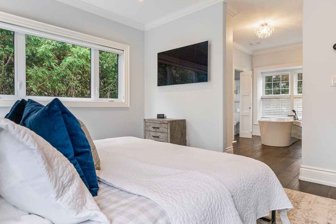 Cozy bedroom with a bed, blue pillows, and a TV on the wall