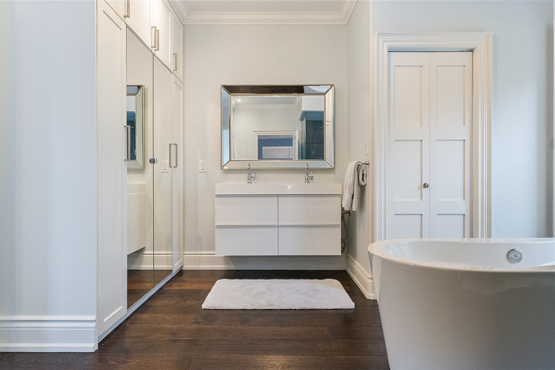 Modern bathroom with a freestanding tub, large mirror, and wooden flooring