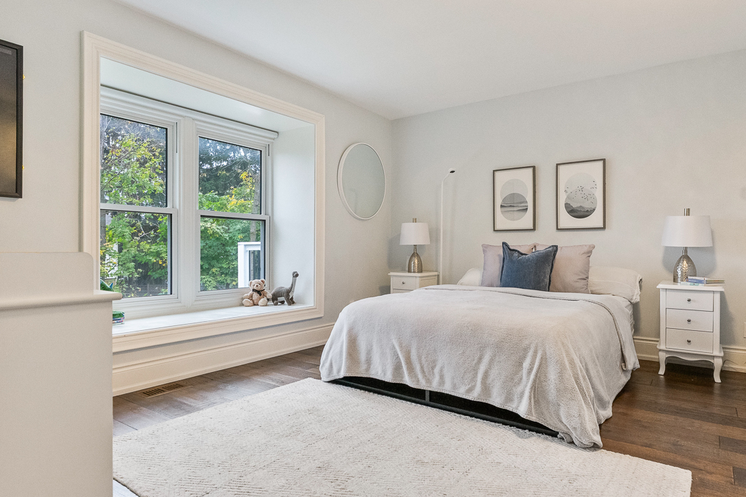 Bright bedroom with a large window, light bedding, and decorative artwork