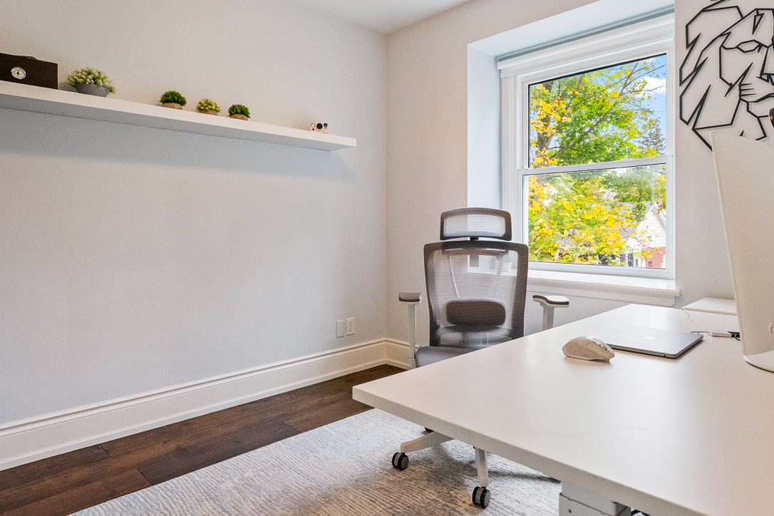 Modern office space with a desk, ergonomic chair, and window view.