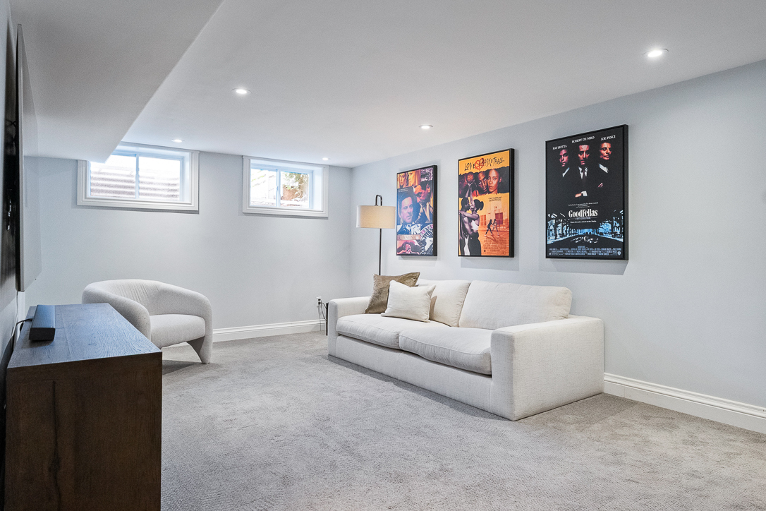Cozy basement living area with a white sofa and movie posters on the wall