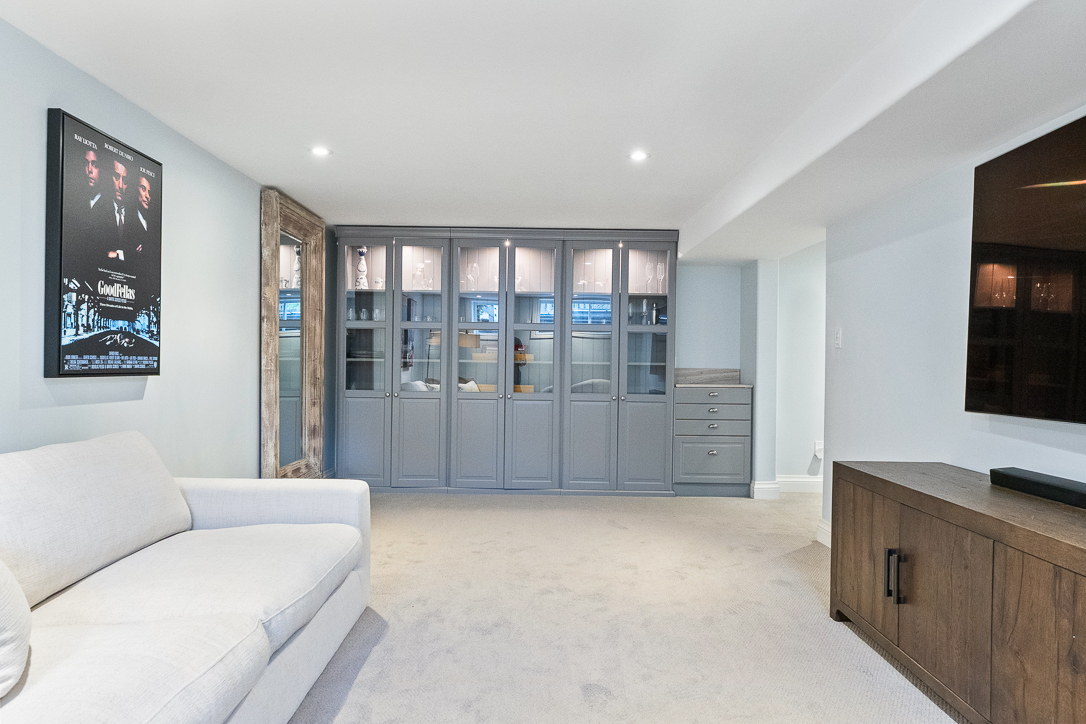 Modern living room with a white sofa, gray cabinetry, and wall-mounted TV
