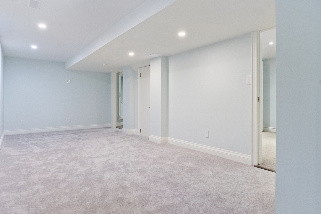 Spacious, light blue basement with carpet and recessed lighting