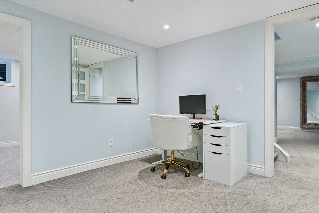 Modern home office with a white desk, chair, and mirror on light blue walls