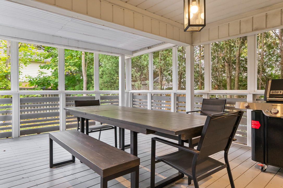 Covered outdoor dining area with a table, benches, and grill