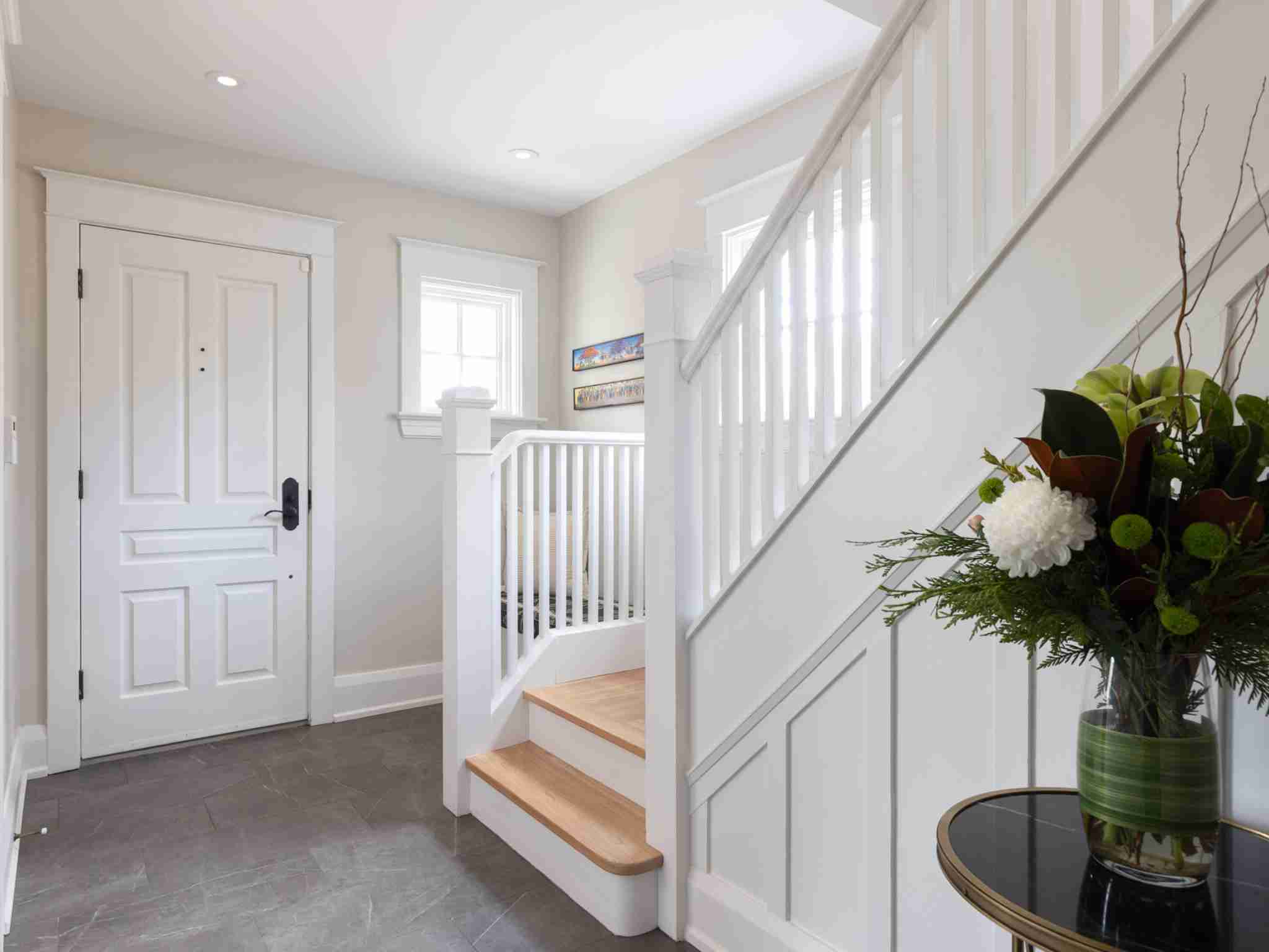 Front foyer and dark tiles and bright white stair case leading to second floor