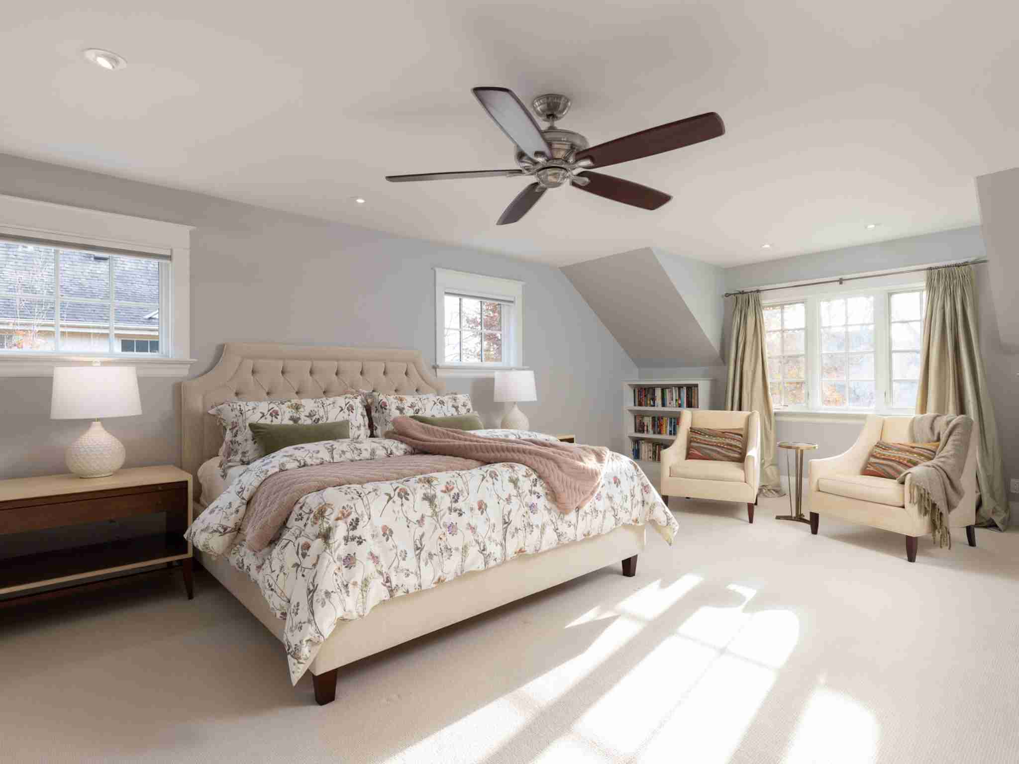 large bedroom with ceiling fans and windows