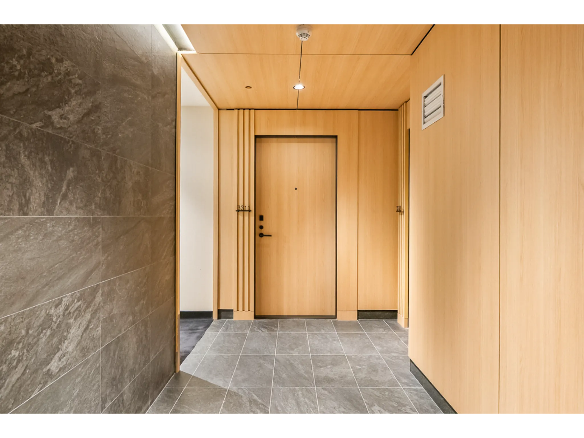 Front entrance into the unit. Wood paneling walls and dark tile flooring