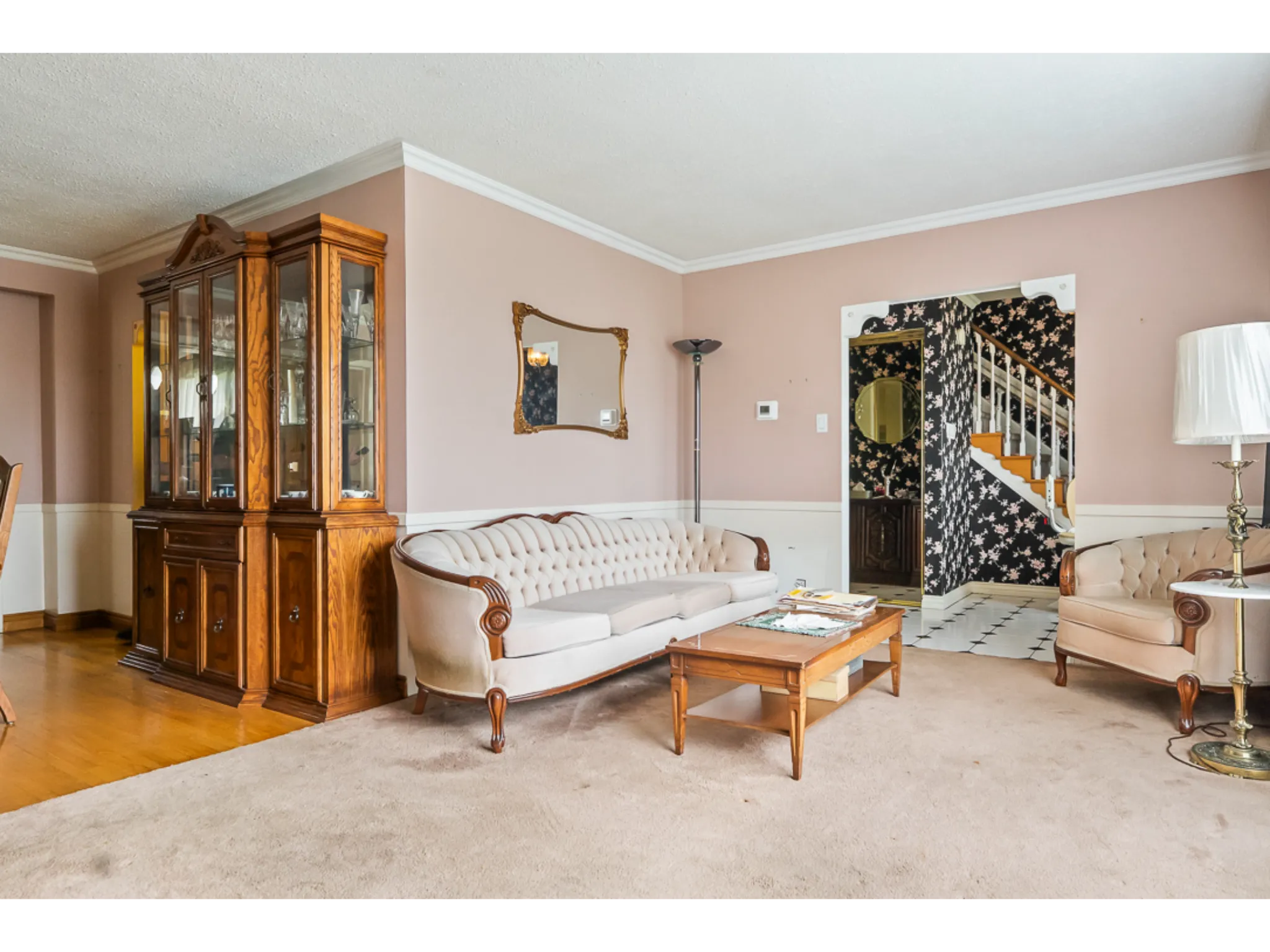 carpeted living room leading into dining room with hardwood flooring