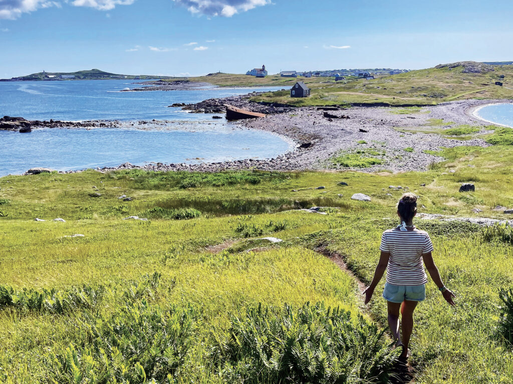 a woman walking on a grassy field by a body of water