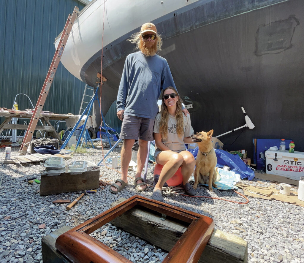 a man and woman with a dog in front of a boat