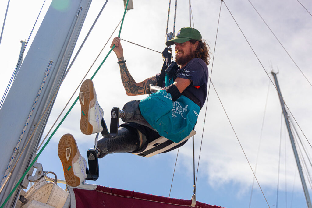 A sailor/ amputee climbs the mast of a sailboat