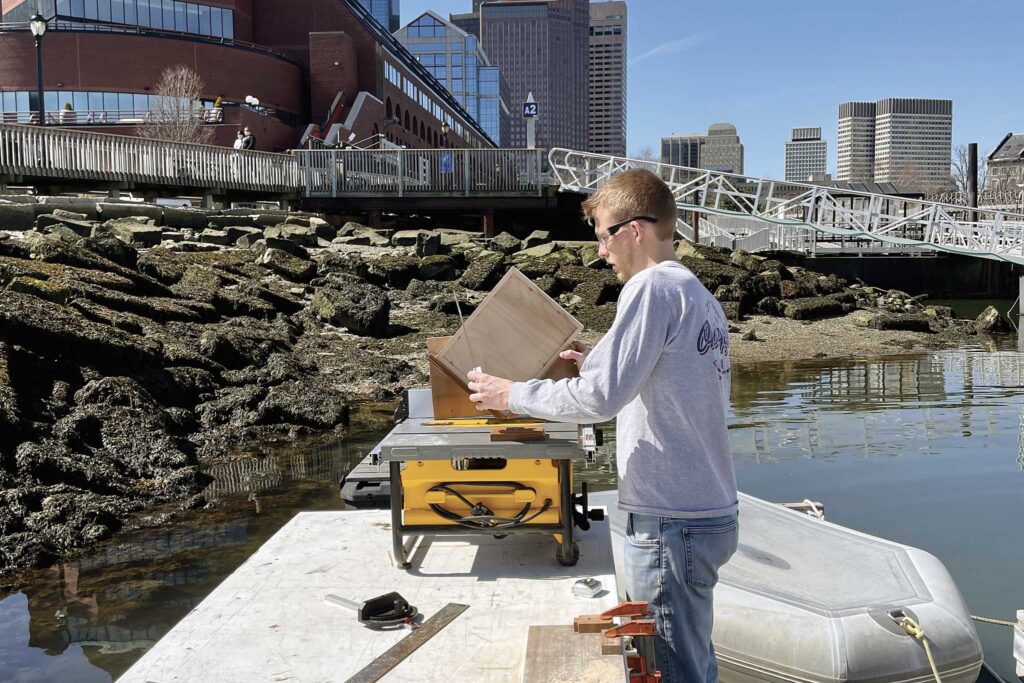 A guy wearing his safety glasses working on with a table saw on a dock.