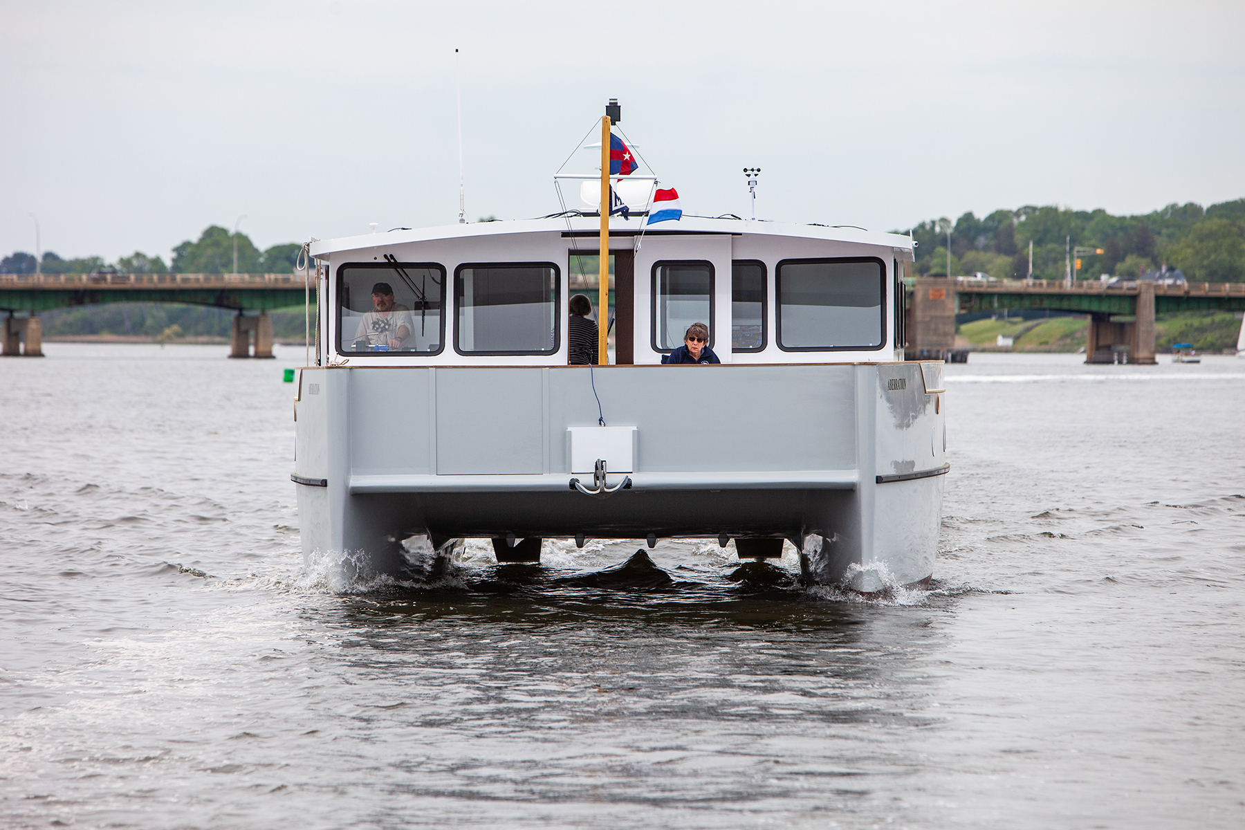 A short white motored catamaran on the water on an overcast day.