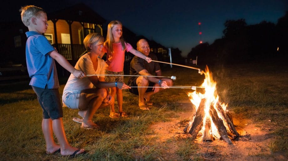 Family roasting marshmallows by campfire