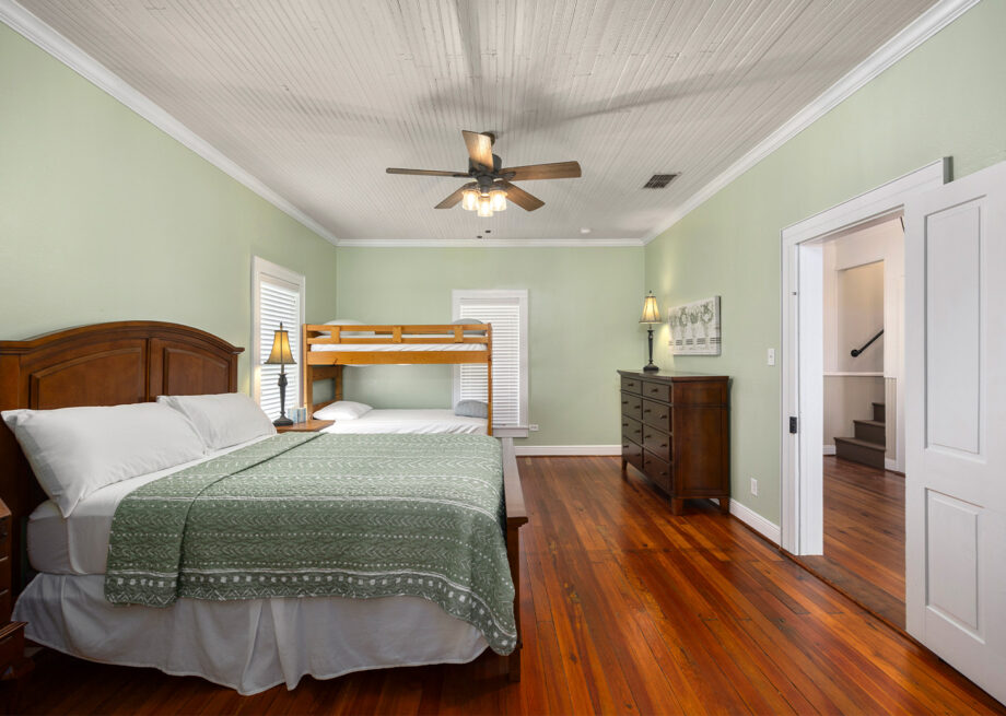 Light green bedroom with a bed and bunkbeds at the 1909 Hotel at Splashway Campground.