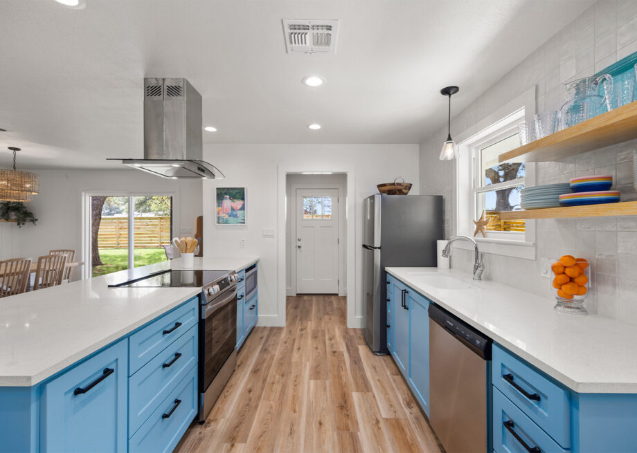 Open concept kitchen with white walls and countertops, as well as blue cabinets.