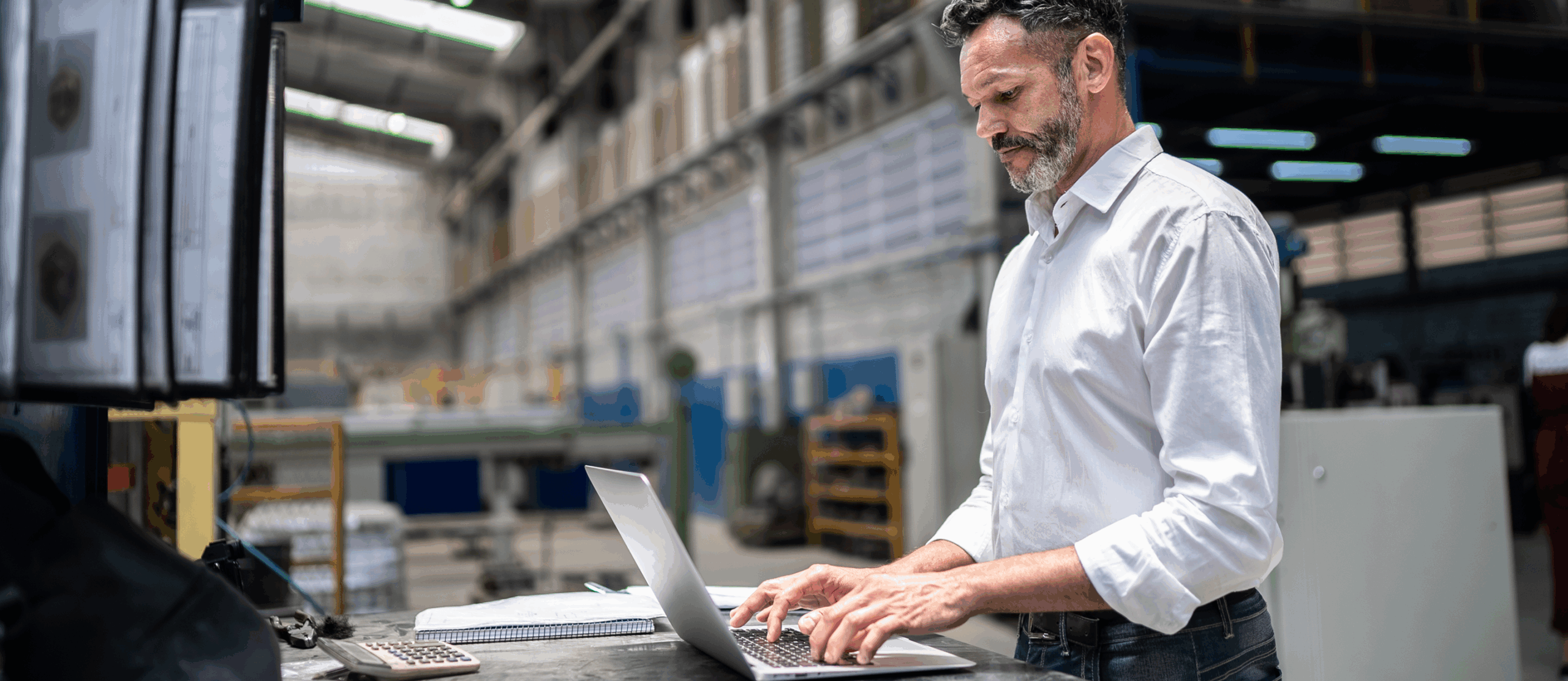 Man working on a laptop in a warehouse setting