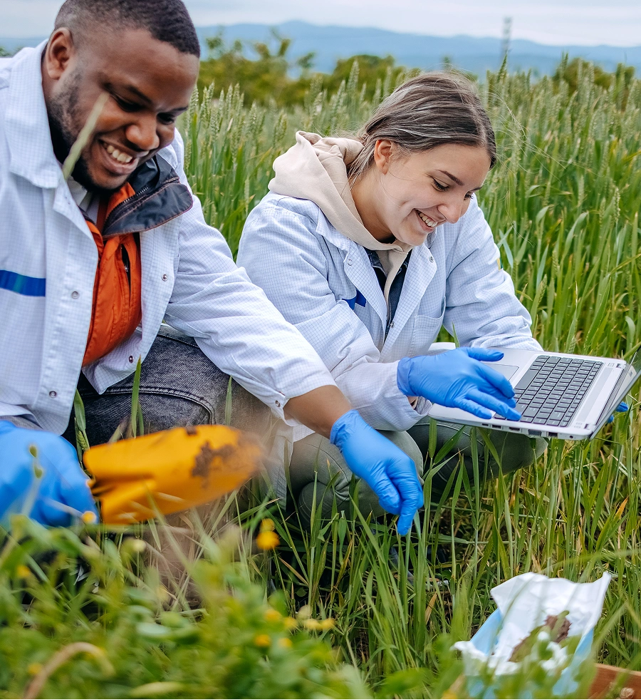 Two people working in a field with a laptop
