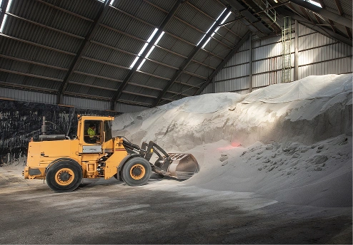 Yellow loader moving material in a large warehouse with high ceilings