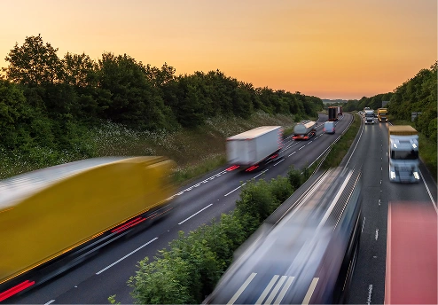 Trucks and vehicles moving along a highway at sunset
