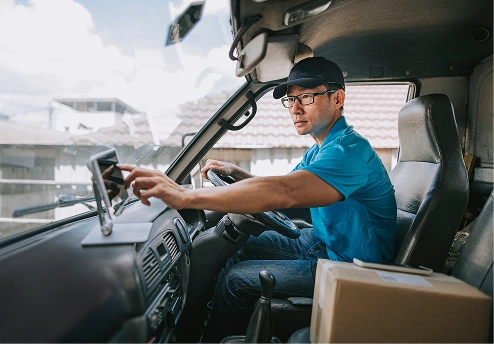 Delivery driver adjusting GPS in a truck's cabin with packages visible