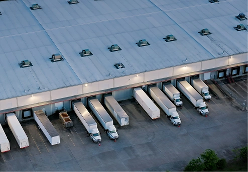 Trucks parked at a warehouse loading dock at dusk