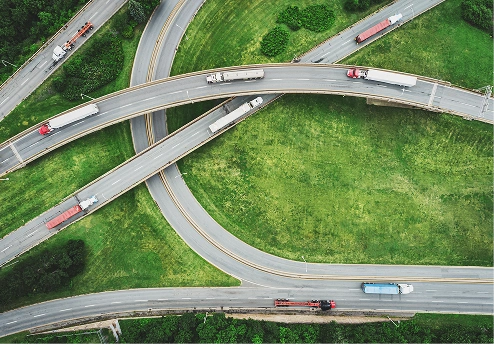 Aerial view of winding highways with trucks and green grass areas