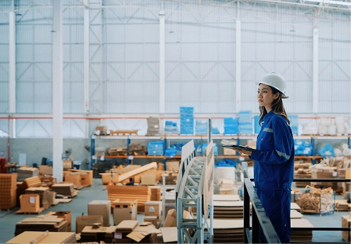 Woman in a hard hat standing in a warehouse filled with boxes
