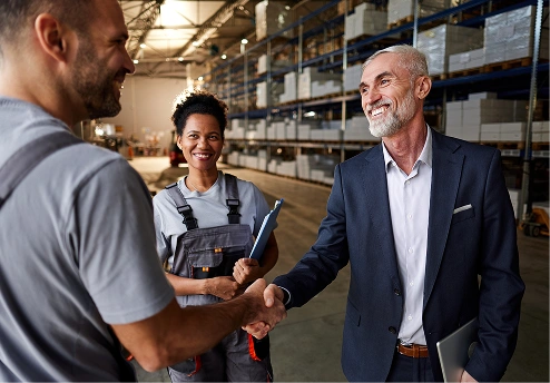 Professionals shaking hands in a warehouse with shelves in the background